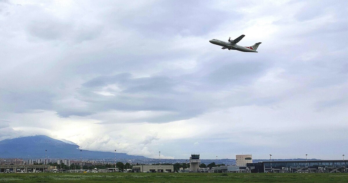 Un aereo in decollo dall'aeroporto di Catania Fontanarossa con l'Etna sullo sfondo